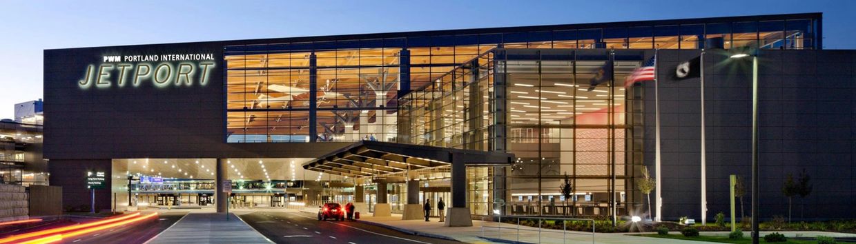 Portland International Jetport terminal building illuminated at dusk.