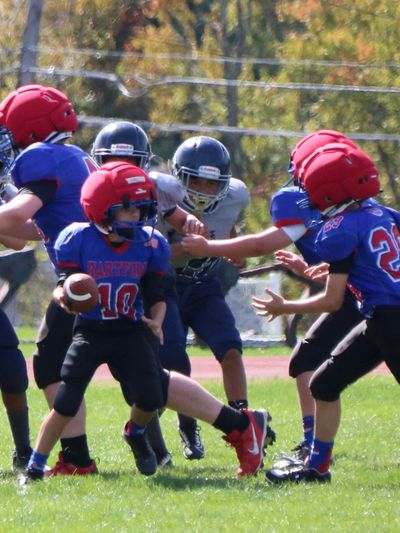 Youth football players in action during a game on a sunny day.