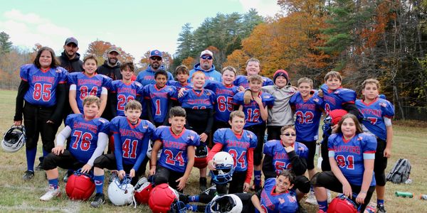 The Hartford Mini-Canes 4th & 5th grade team photo on the field in their blue jerseys with fall foli