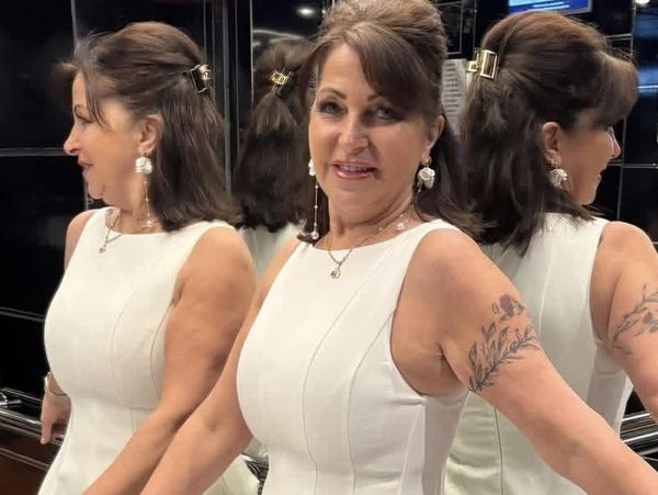 Woman in white dress posing in an elevator with mirrored walls.