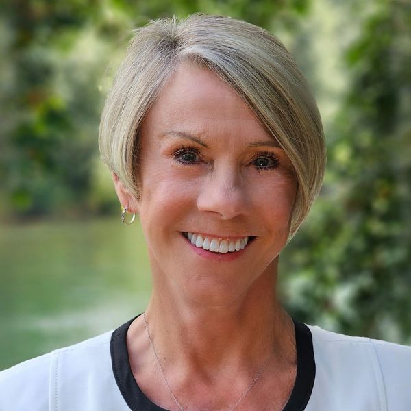 Smiling woman with short blonde hair outdoors.