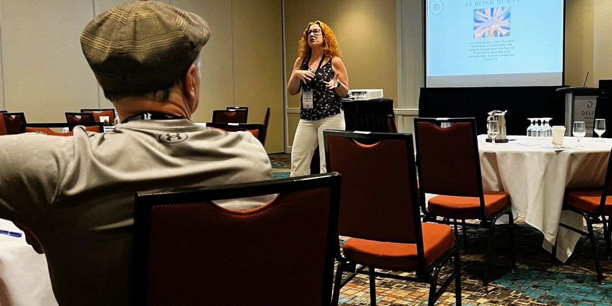 A woman presents in a small conference room to a few attendees.