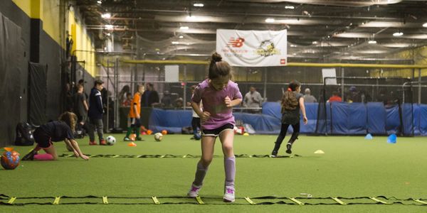 Youth soccer player engaged in an agility drill using a floor ladder