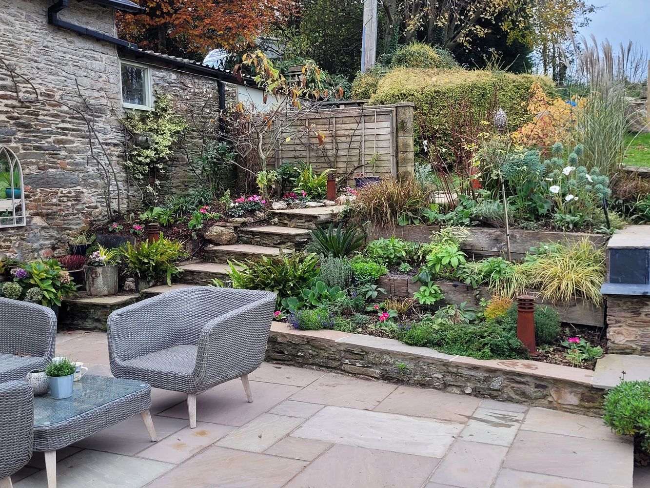 Cozy outdoor patio with wicker chairs and lush garden beds.