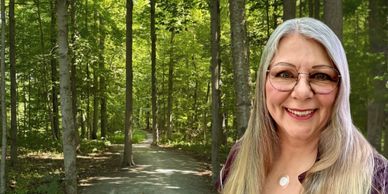 Woman smiling in a forest representing wearable light support wellness approach