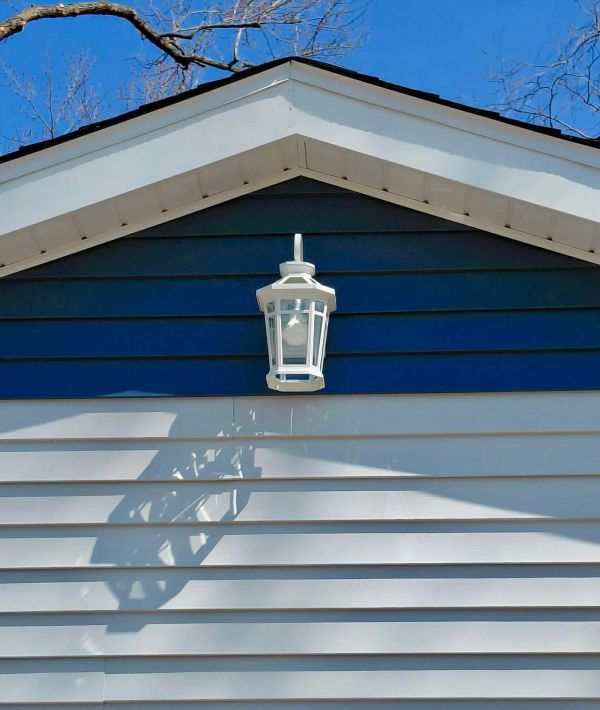 White outdoor lantern casting a shadow on blue and white siding.
