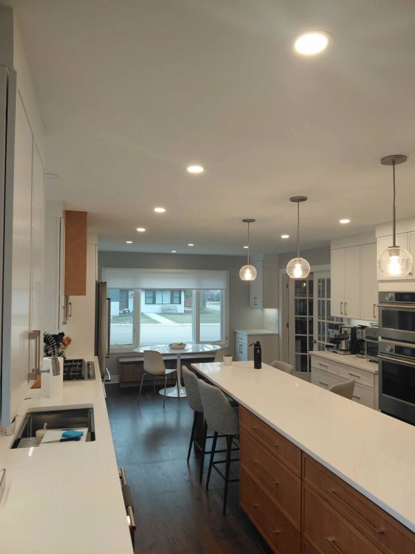 Modern kitchen with white countertops, wooden cabinets, and pendant lighting.