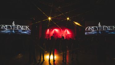 Concert stage with red lights and Greyhawk banners.