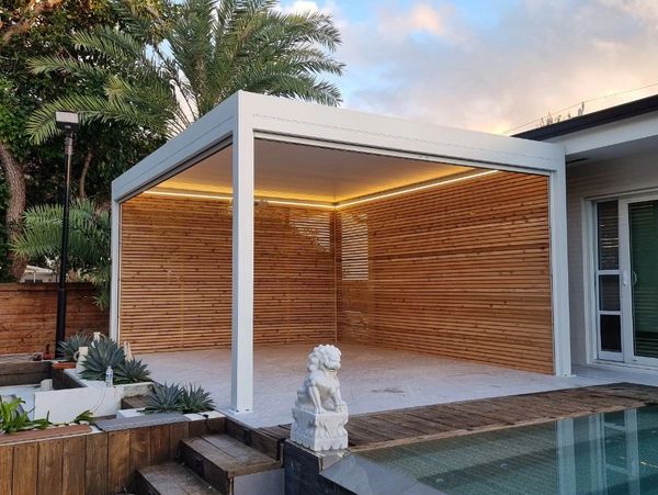 Modern poolside pergola with wooden slat walls and ambient lighting.