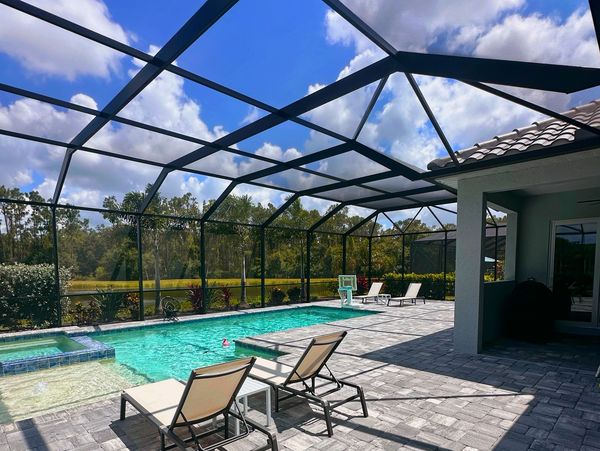 Screened-in outdoor pool area with lounge chairs on a sunny day.