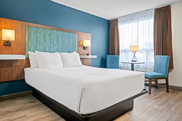Modern hotel room with a bed and seating area.