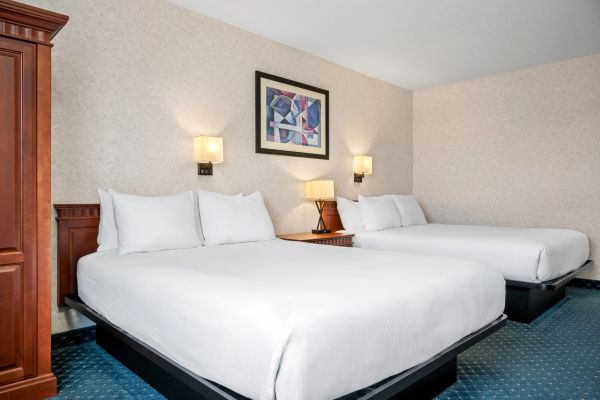 Hotel room with two large beds and a nightstand.