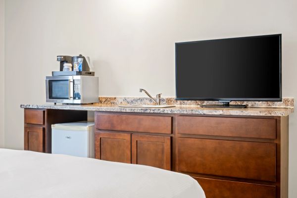 TV, microwave, and coffee maker on a wooden counter in a room.