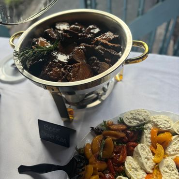 Buffet setup with beef short ribs and a colorful salad platter.