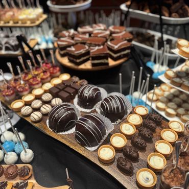 A variety of elegant desserts including chocolate balls, tarts, and mini cakes.