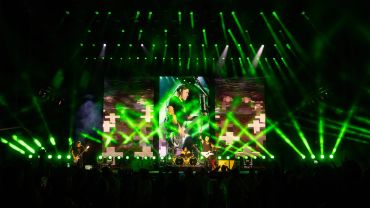 Band performing on stage with green lights.
