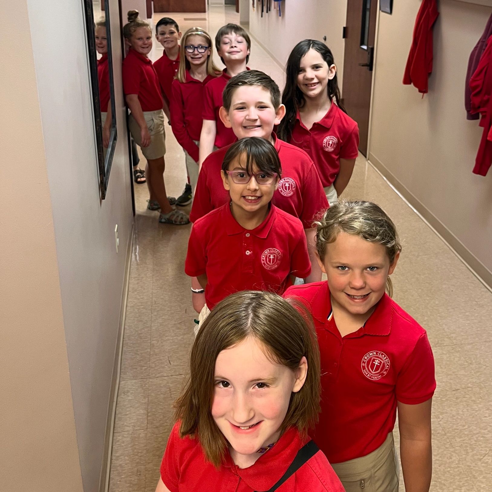 Line of smiling children in red school uniforms.