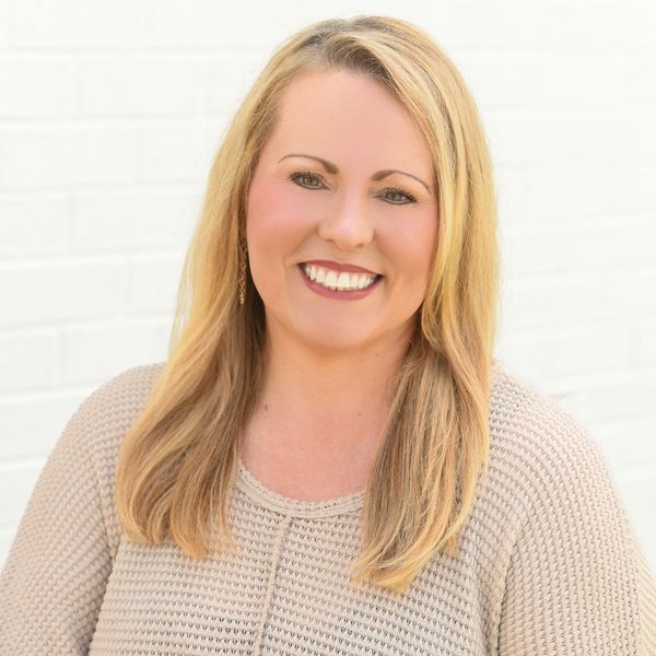 Smiling woman with blonde hair in beige sweater.