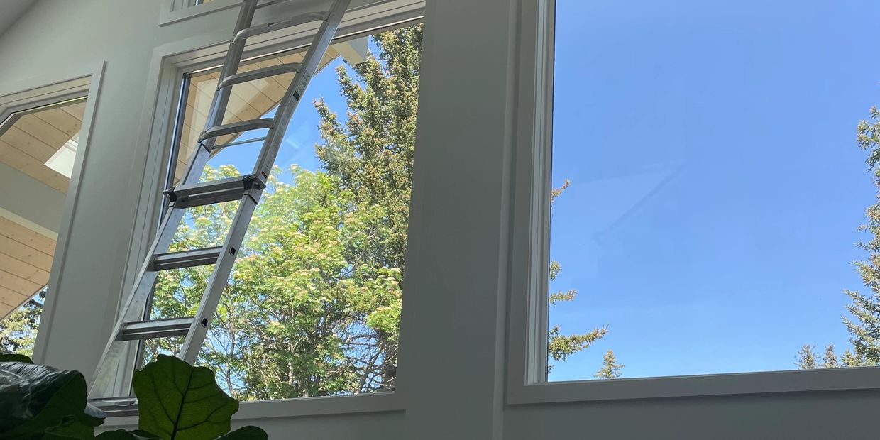 Ladder leaning against tall indoor windows for window cleaning service.