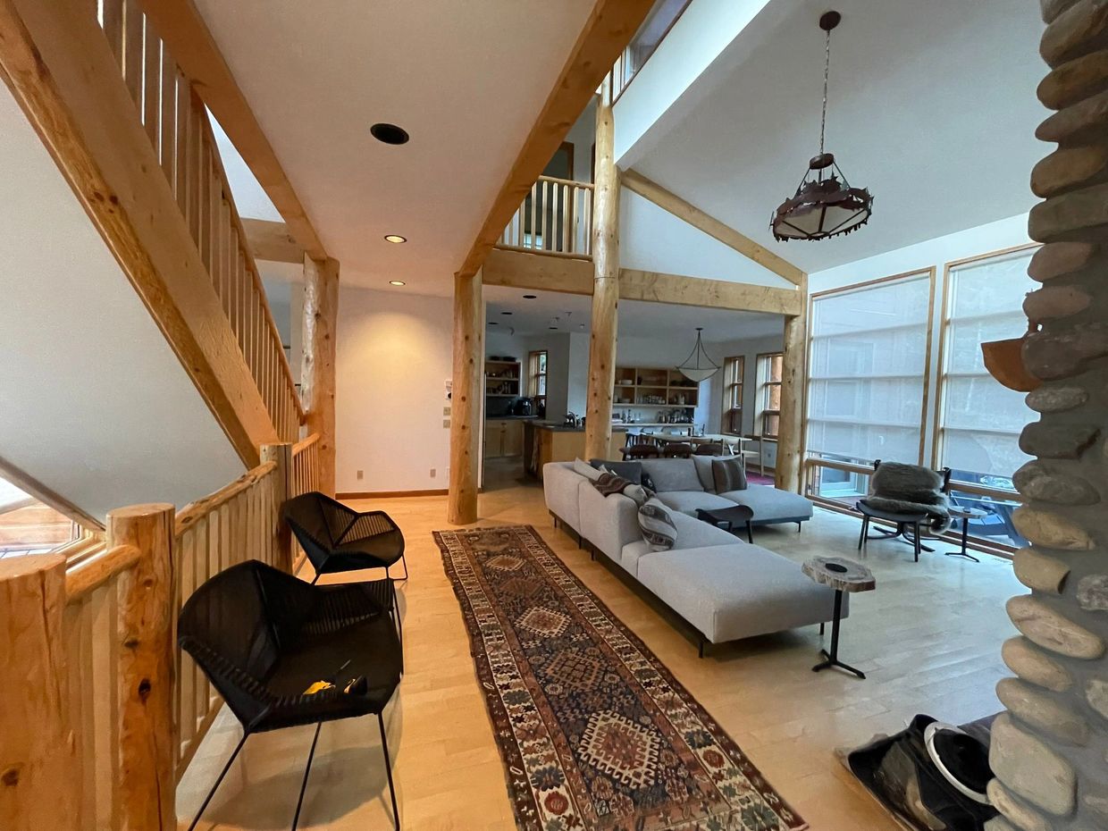 Canmore Home Maintenance. Spacious living area with wooden beams, modern furniture, and large windows.