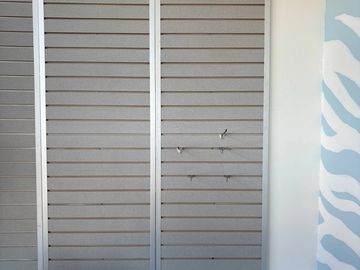 Empty slatwall panels on a wall with hooks.