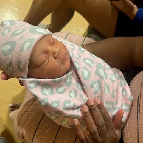 Newborn baby peacefully sleeping wrapped in a pink blanket.