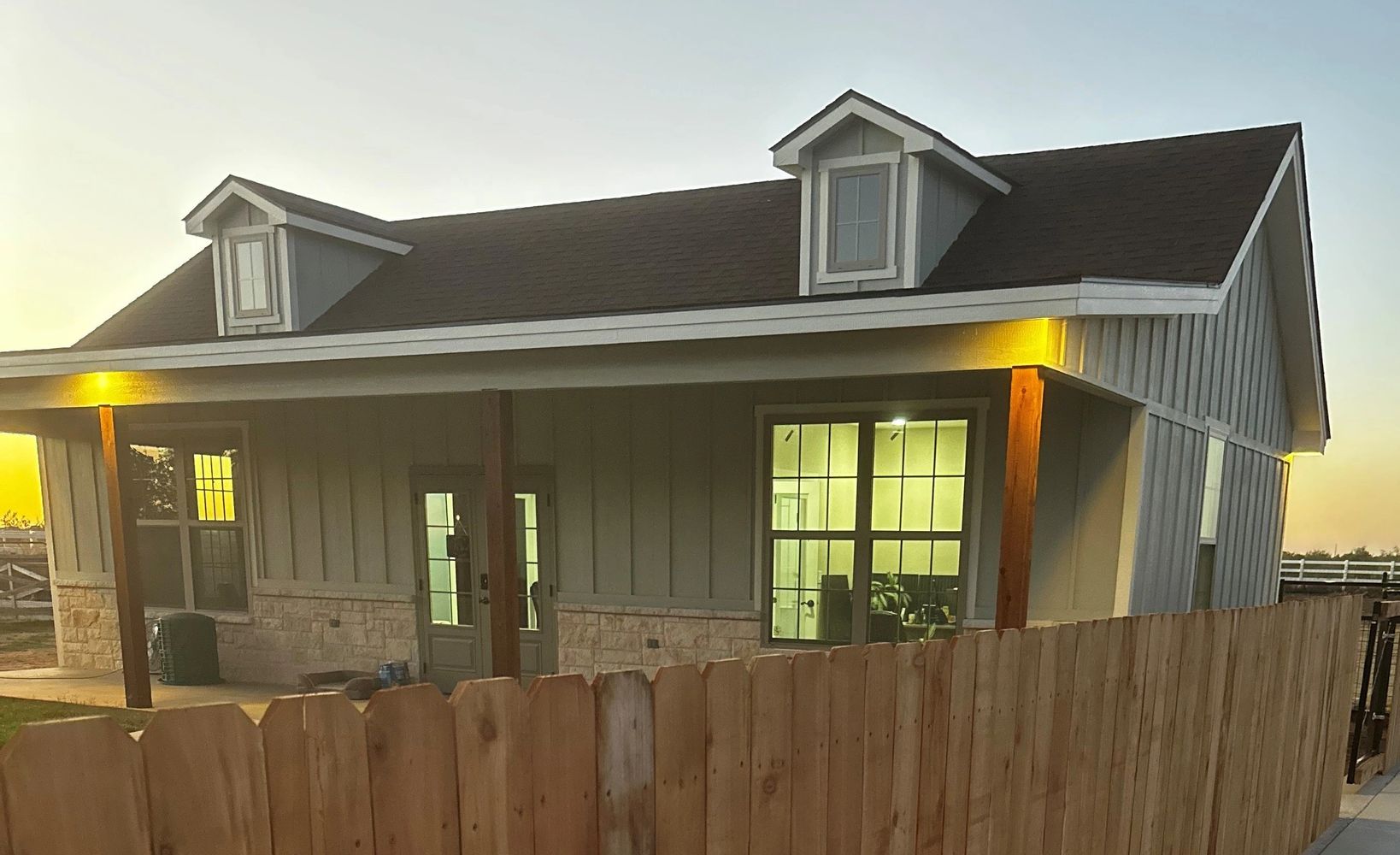Black pencils in a gray holder next to a stack of white magazines with a camera in the background.