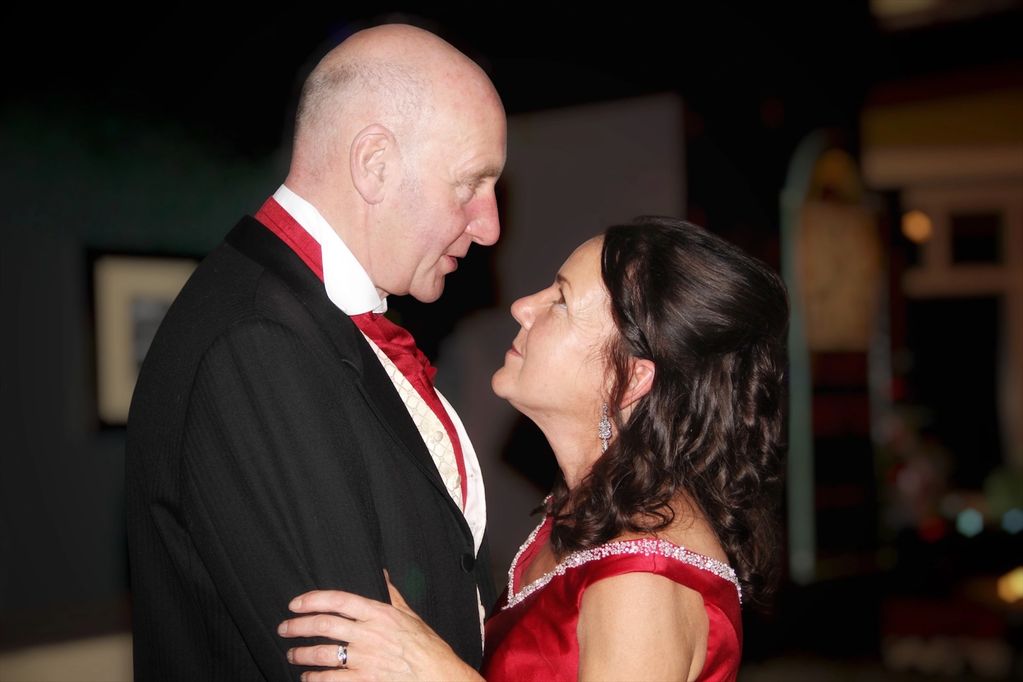 A couple dressed in formal attire gazing lovingly at each other.