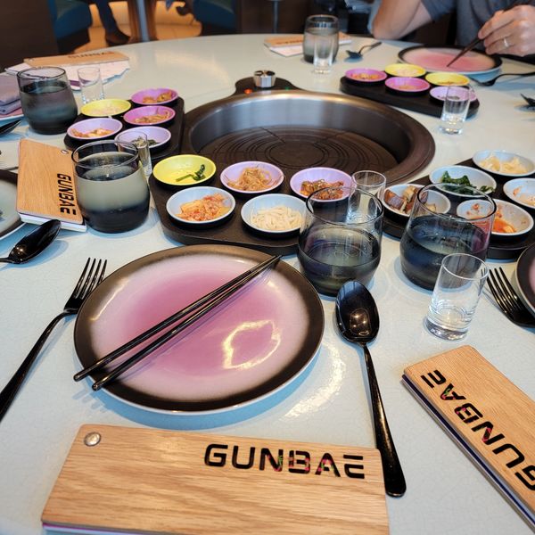 Table setup at Gunbae Korean BBQ with chopsticks, plates, and side dishes.