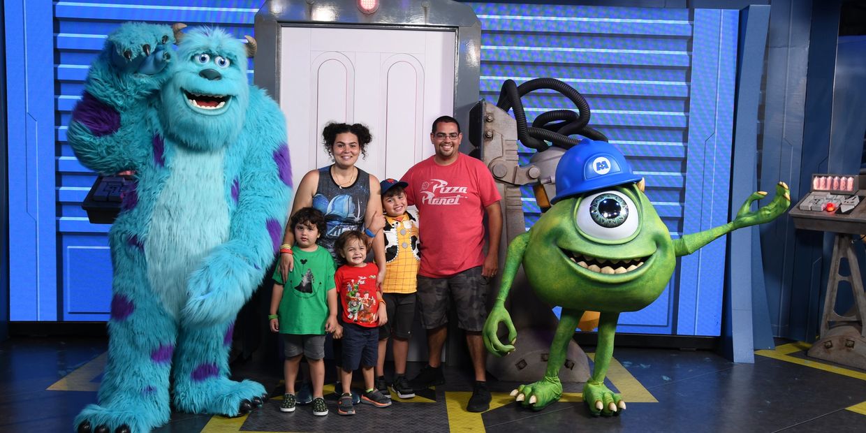 Family posing with Sulley and Mike from Monsters, Inc. at a theme park.