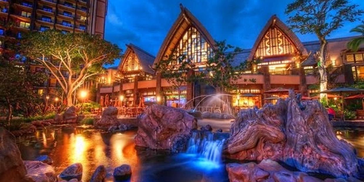 Illuminated resort with waterfall and rocks at twilight.