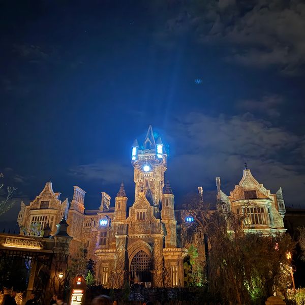 A spooky, illuminated castle at night with glowing blue lights on the tower.
