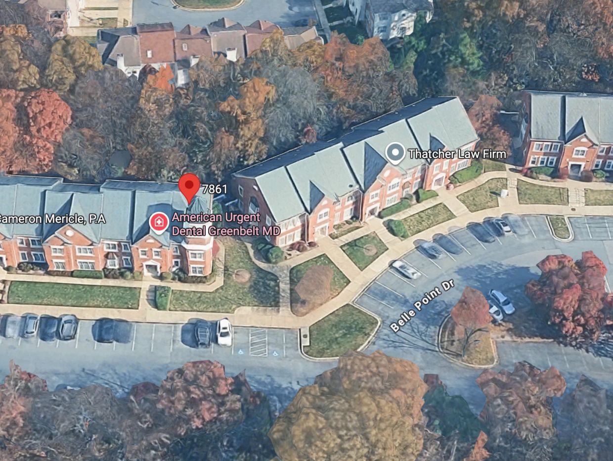 Aerial view of a business complex with parking and trees.