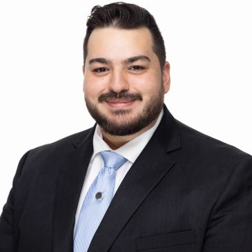 Smiling man in a suit and light blue tie.