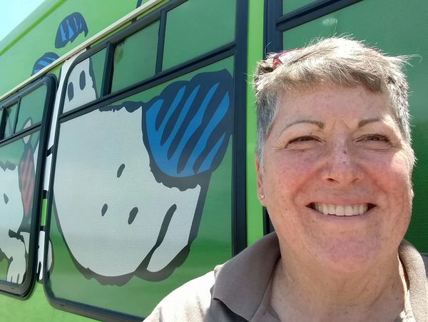 Smiling woman standing in front of a colorful bus
