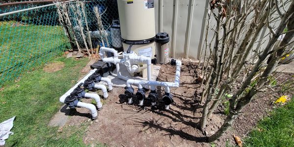 Outdoor pool filtration system with multiple valves and pipes.