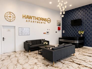 Modern apartment lobby with black sofas and marble flooring.