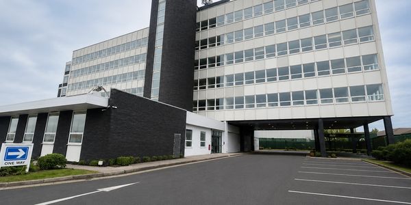 Modern office building with large windows and a one-way sign in front.