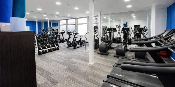 Modern gym with treadmills, exercise bikes, and free weights in a bright room.