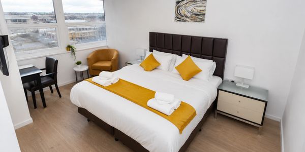 Bright hotel room with a large bed and mustard accents.