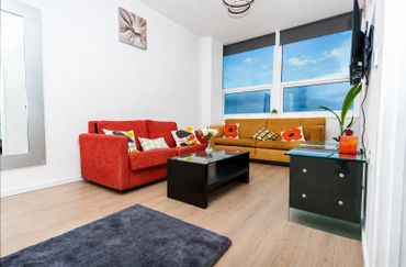 Cozy living room with vibrant sofas and large window views.
