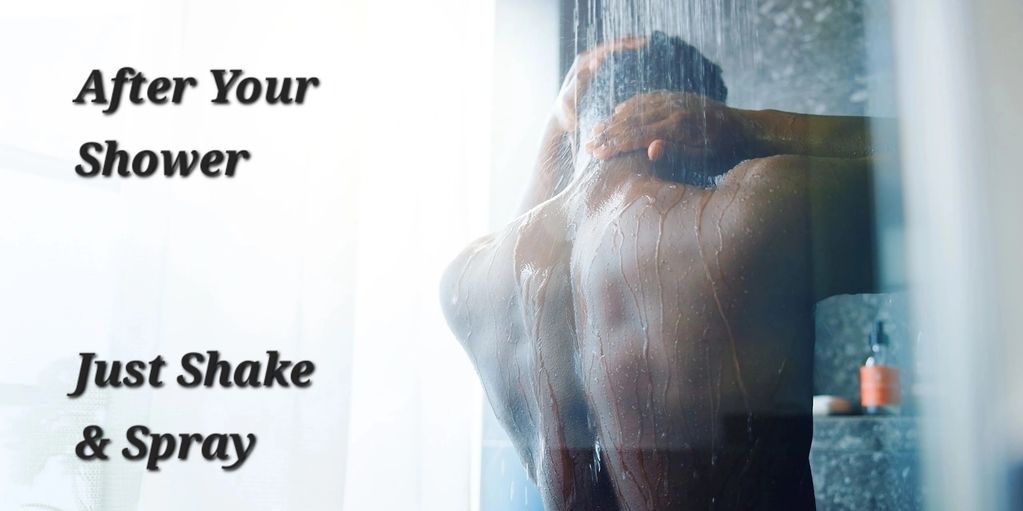 A man taking a shower, he is rubbing his head while standing under the shower head. 