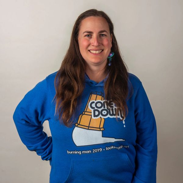 Woman smiling in a blue Burning Man 2019 hoodie.