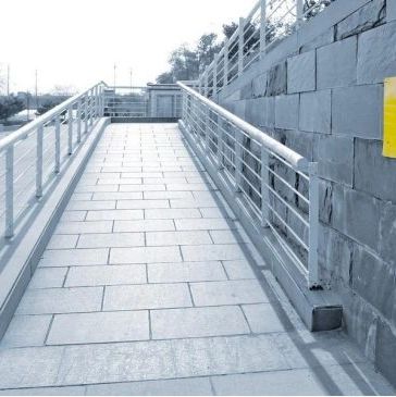 A wheelchair-accessible ramp with metal railings and a handicap sign on the wall.