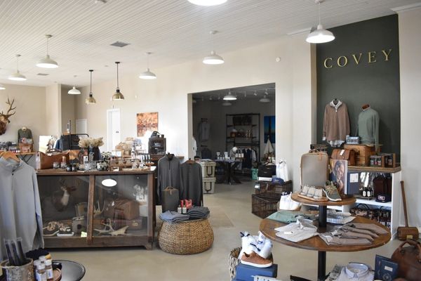 Interior of a stylish boutique named COVEY with clothing and accessories displayed.