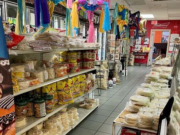 Interior of a store with shelves stocked with various packaged food items and colorful hanging decorations.