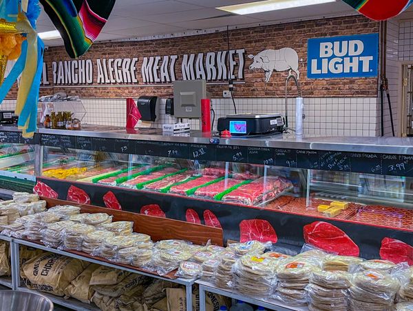 Interior of a meat market with packaged tortillas and meat display.
