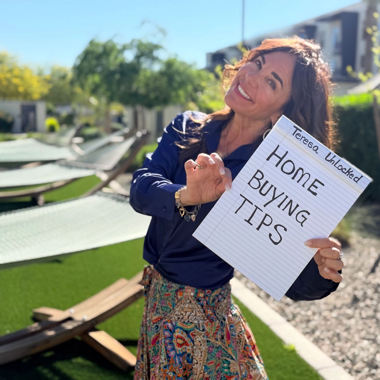 Smiling woman holding a sign with home buying tips outdoors.
