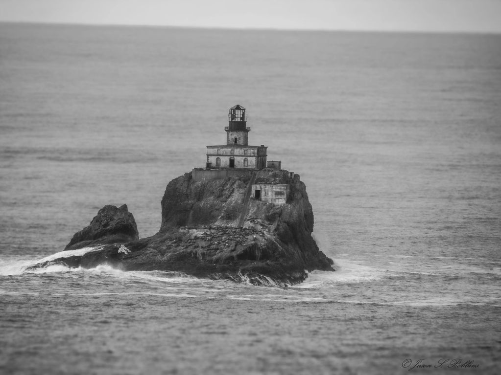 Old abandoned lighthouse on rocks with seals lying around