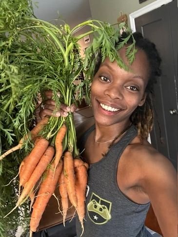 Smiling woman holding fresh carrots.